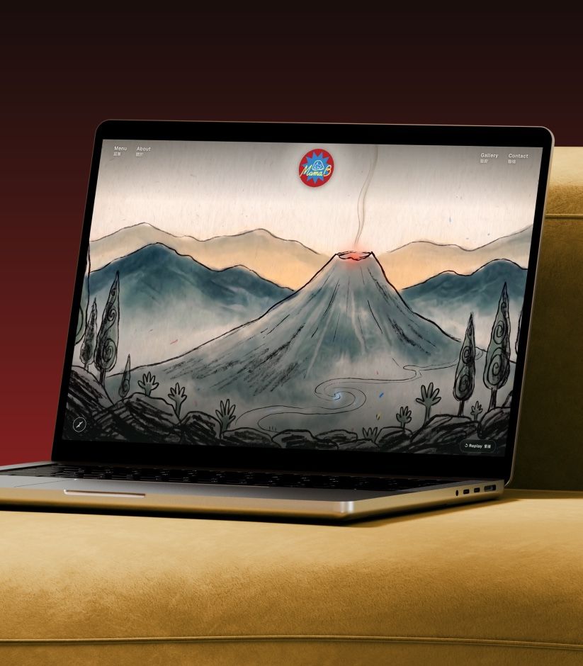 Mama B's website on a laptop resting on a mustard sofa: a hand-drawn ink volcano under the Mama B badge.